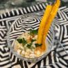 A bowl of creamy dip garnished with herbs and plantain chips.