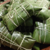 Wrapped food parcels tied with string, covered in green leaves.