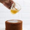 Pouring syrup onto a tall cake.