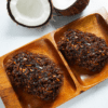 Two coconut-shaped chocolate treats on a wooden tray.