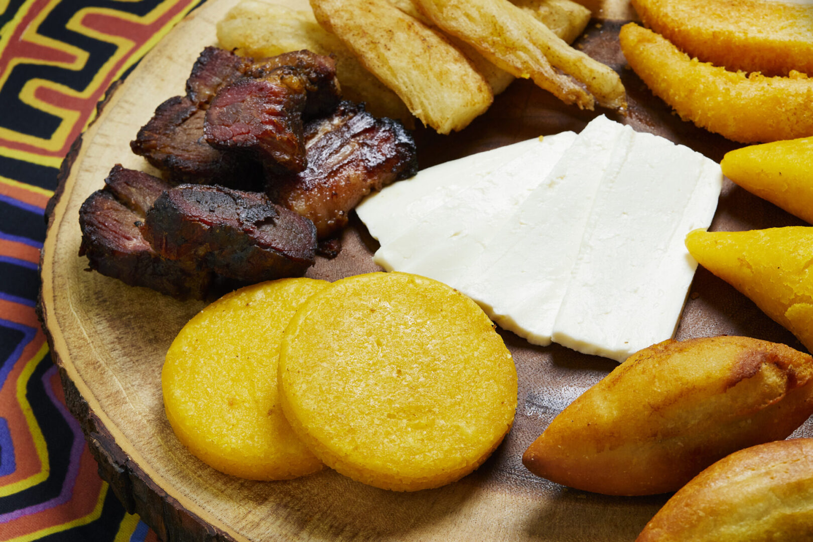 Roasted beef, cheese and wedges on a wooden plate