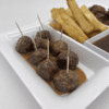 Meatballs with toothpicks and fries served with dipping sauce.