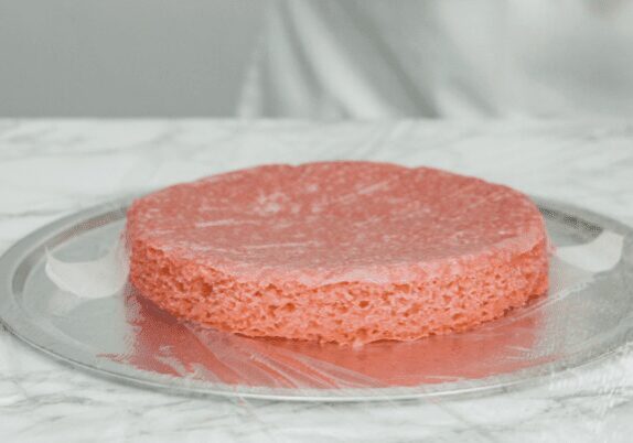 A single pink sponge cake layer on foil.