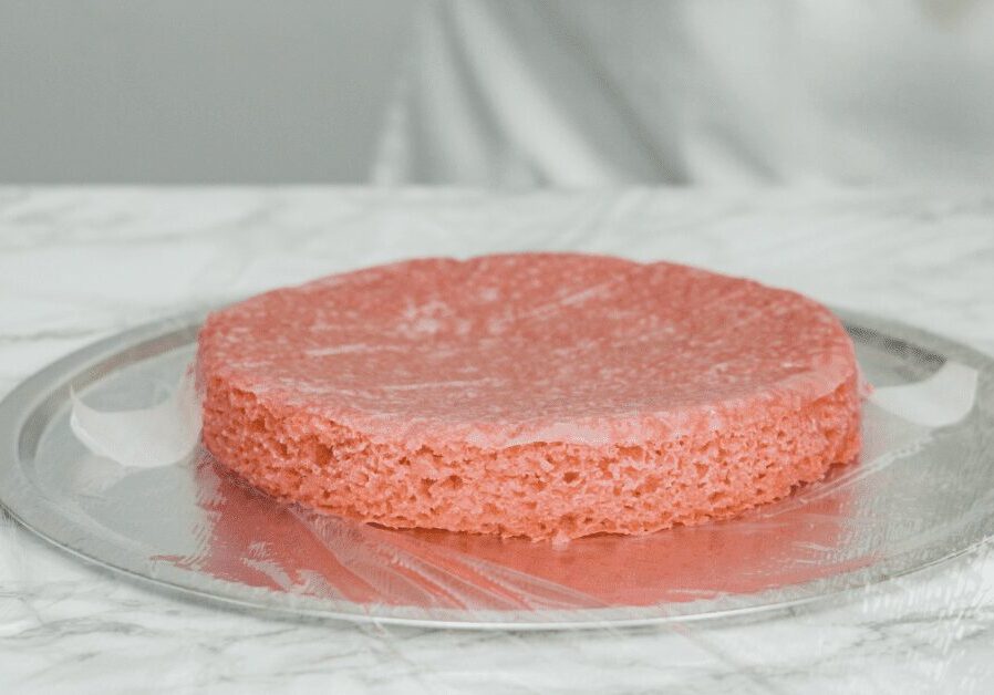 A single pink sponge cake layer on foil.