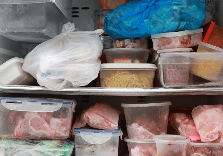 Freezer filled with various frozen meats and packaged food containers.