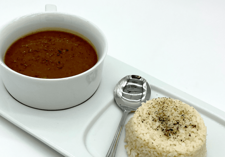 A plate of rice along with a soup in it